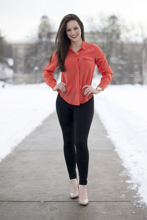 Allie Curtis is wearing an orange blouse from Ann Taylor on top of black pixie pants from J. Crew. Her gold pin and gold necklace are from the Syracuse University bookstore.