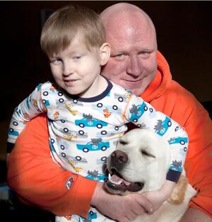 (From left) Jack and Gregg Tweedy, hug their dog Buster, a pet Jack requested after his latest surgery in March. 