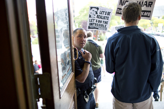 An SPD officer watches as Occupy Syracuse members leave city hall.