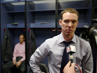 Assistant coach Gerry McNamara (R) of the Syracuse Orange speaks during an interview as assistant coach Mike Hopkins (R) sits in the locker room after their loss to the Michigan Wolverines